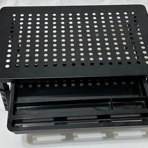 Adjustable height black perforated metal monitor stand with a pull-out drawer. 